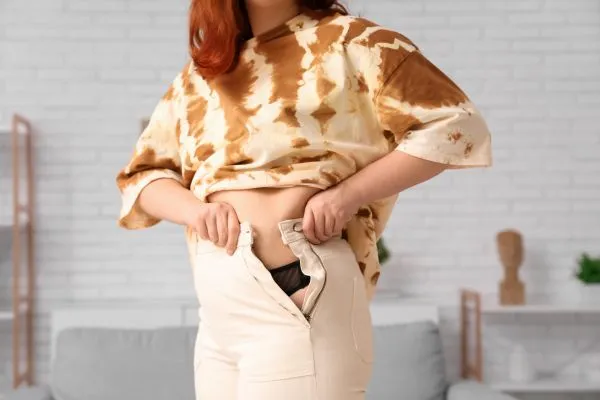 Image of woman trying to do her trousers up after pregnancy weight gain St Helens